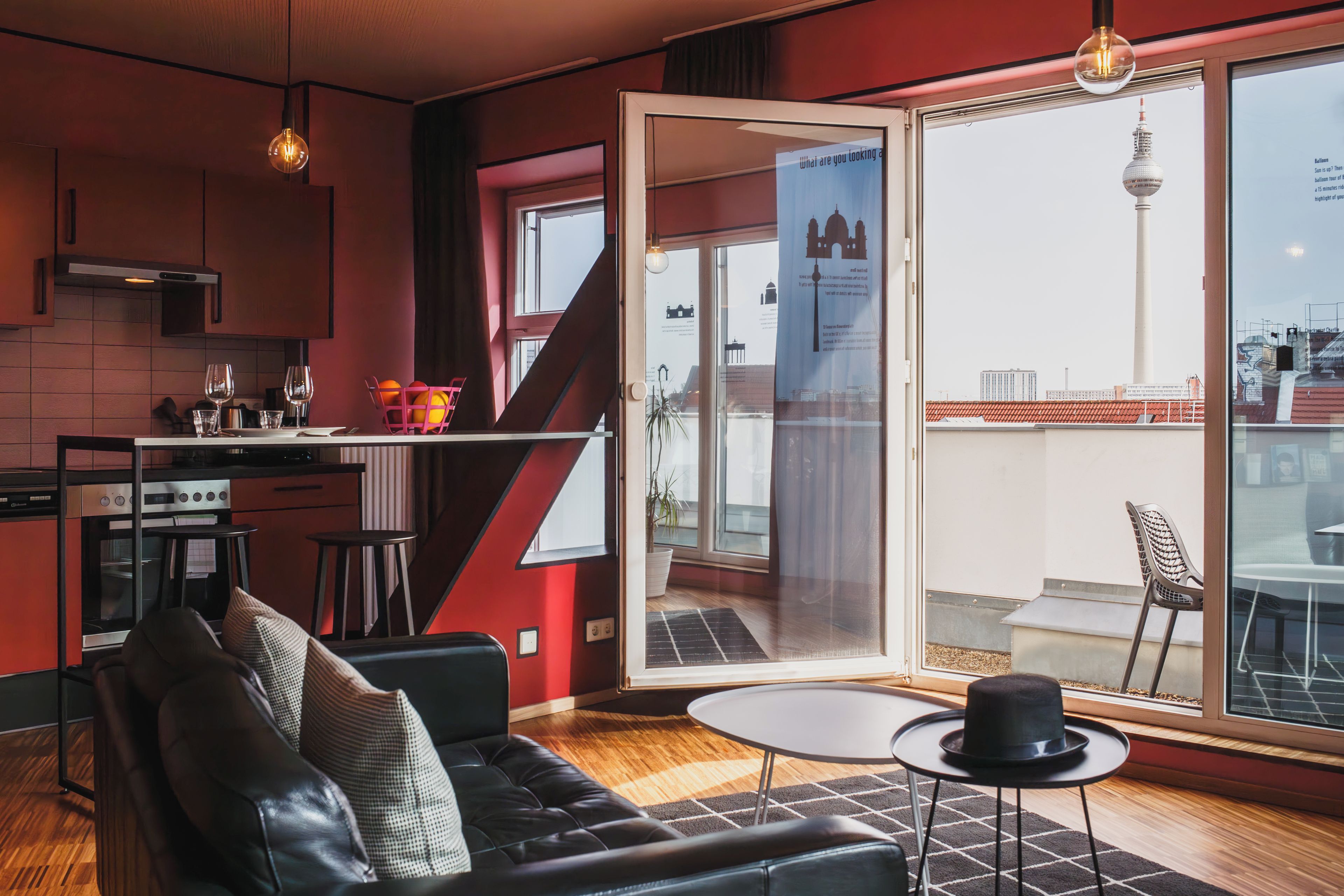 A modern living space with a kitchen, dining area, and a large sliding glass door leading to an outdoor terrace.