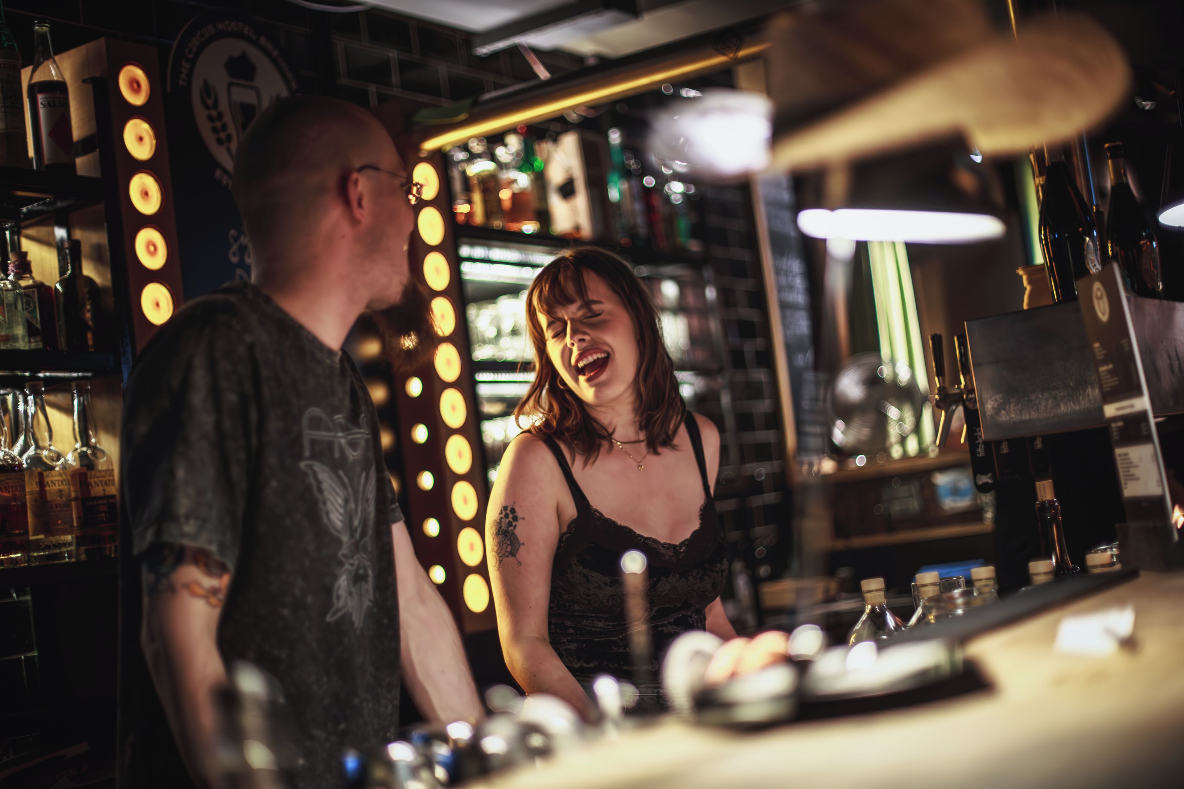 Un bar con barra, botellas y una persona detrás.