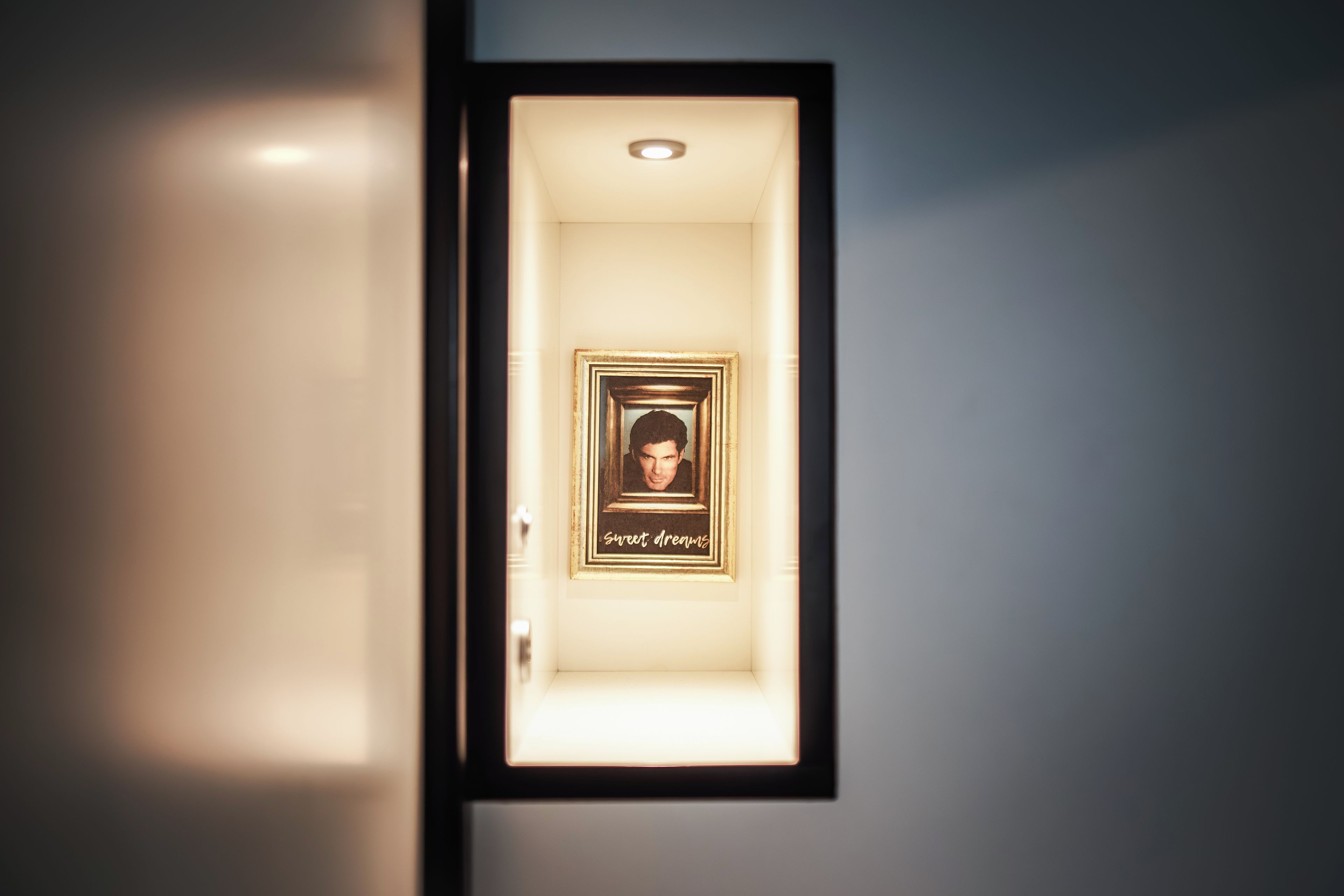 A hallway with a framed picture on the wall and a door at the end.