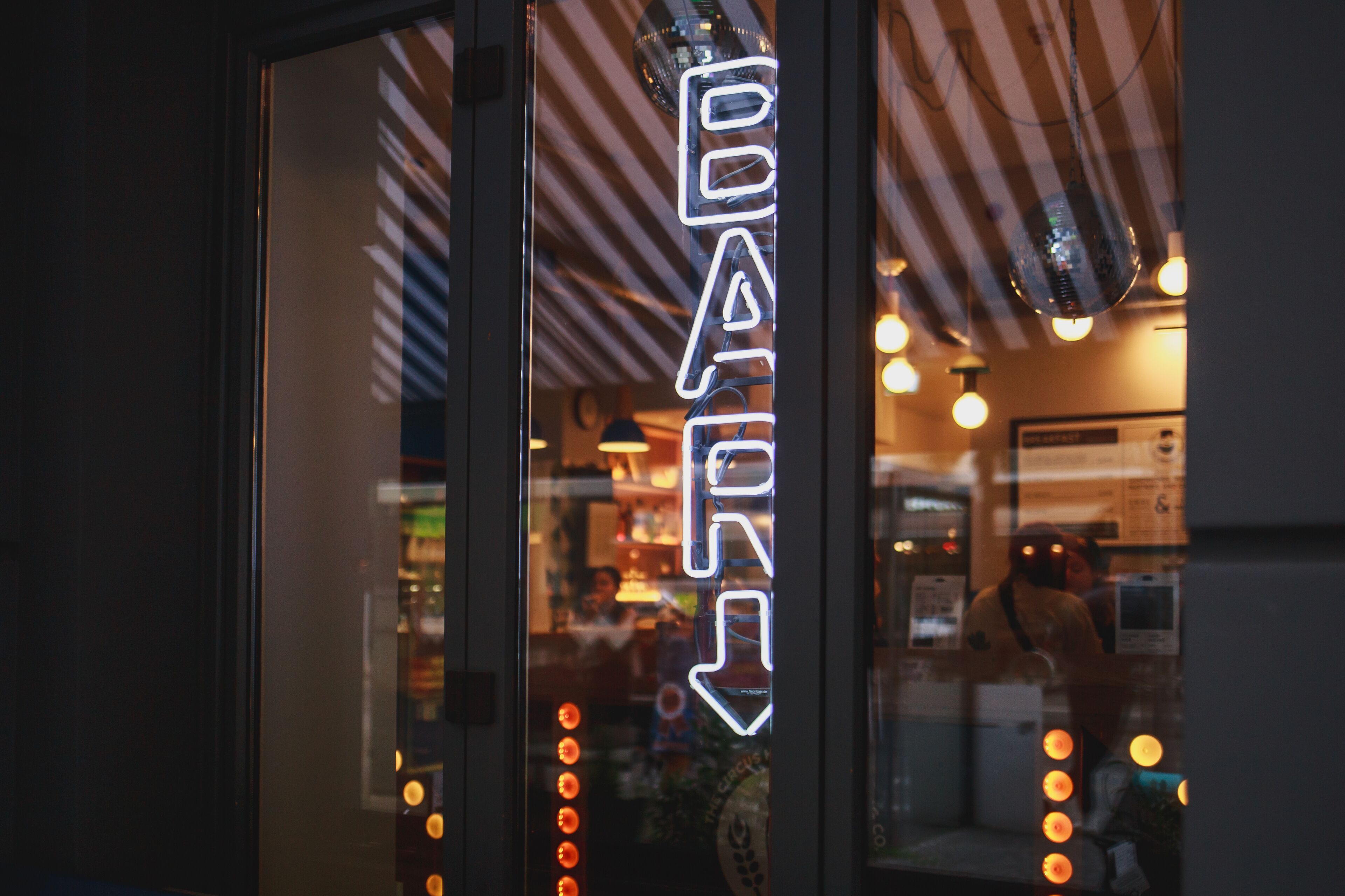A neon sign with the word "BAR" and a downward arrow, indicating a bar area inside.