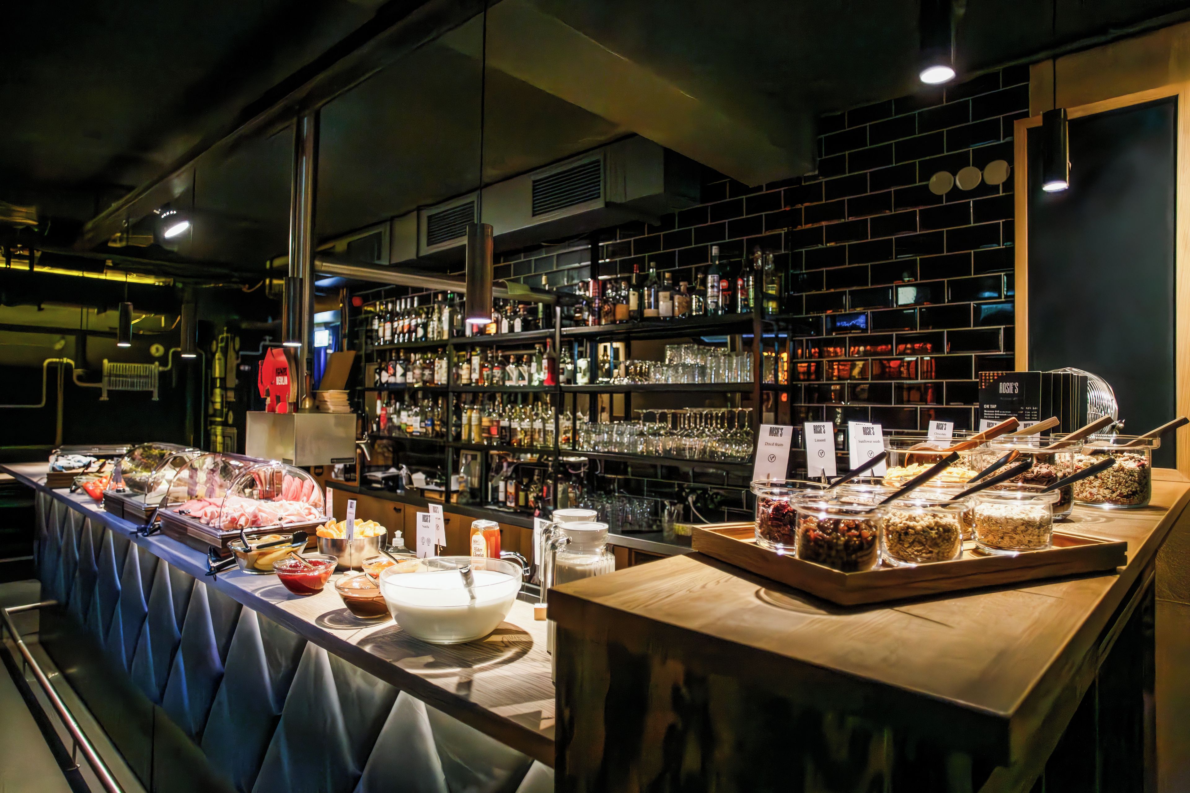 A buffet setup with various food items and a bar area with shelves of bottles and glasses.