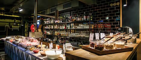 A buffet setup with various food items and a bar area with shelves of bottles and glasses.