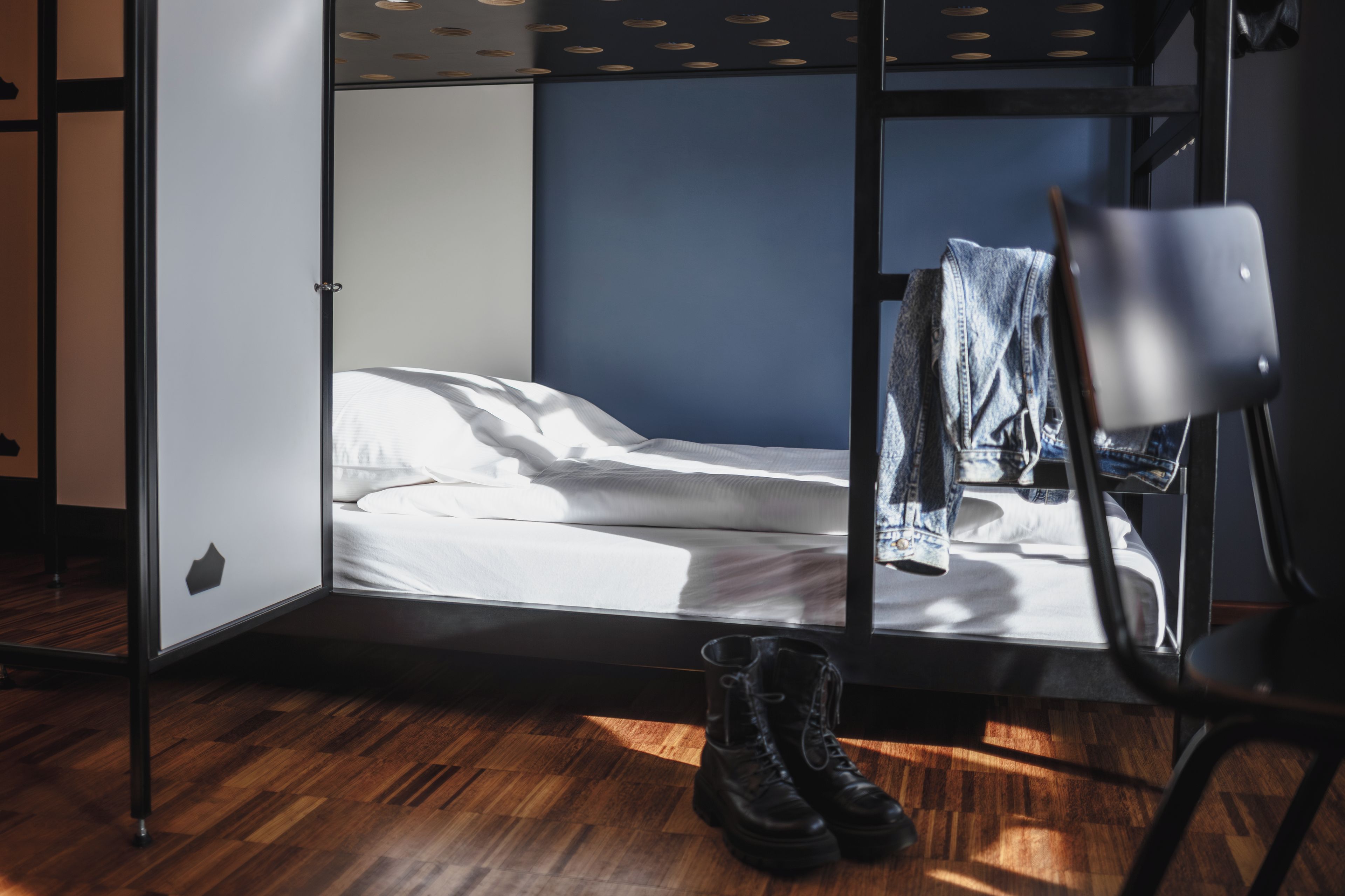 Una habitación con una cama, una silla y un par de botas en el suelo.