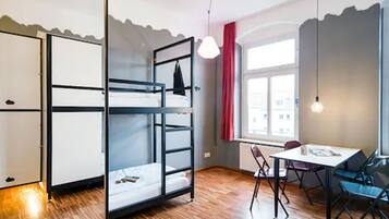 Una stanza con un letto a castello, un tavolo da pranzo con sedie e una finestra con tende rosse.