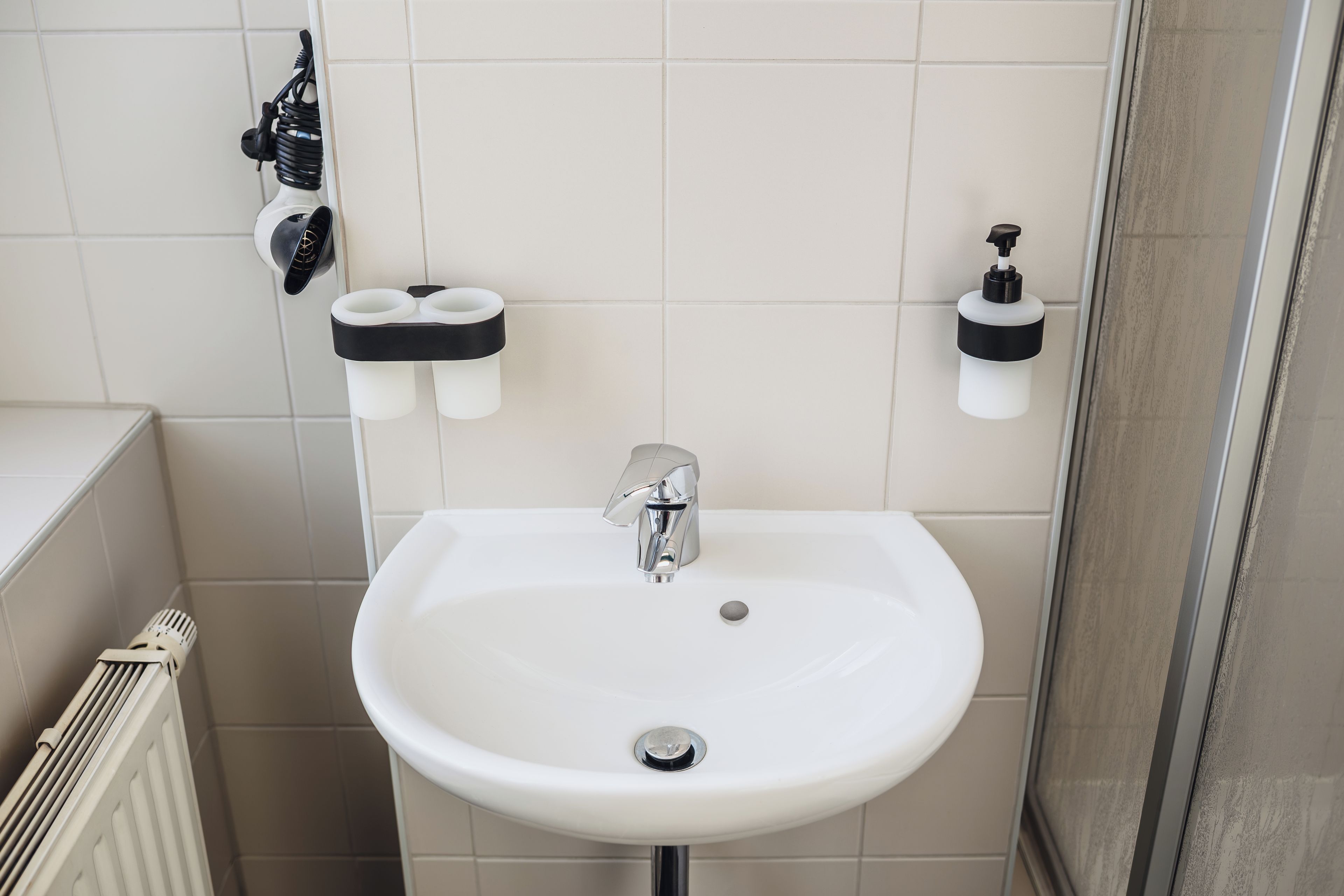 Un baño con un lavamanos blanco, un espejo y dos dispensadores de jabón.