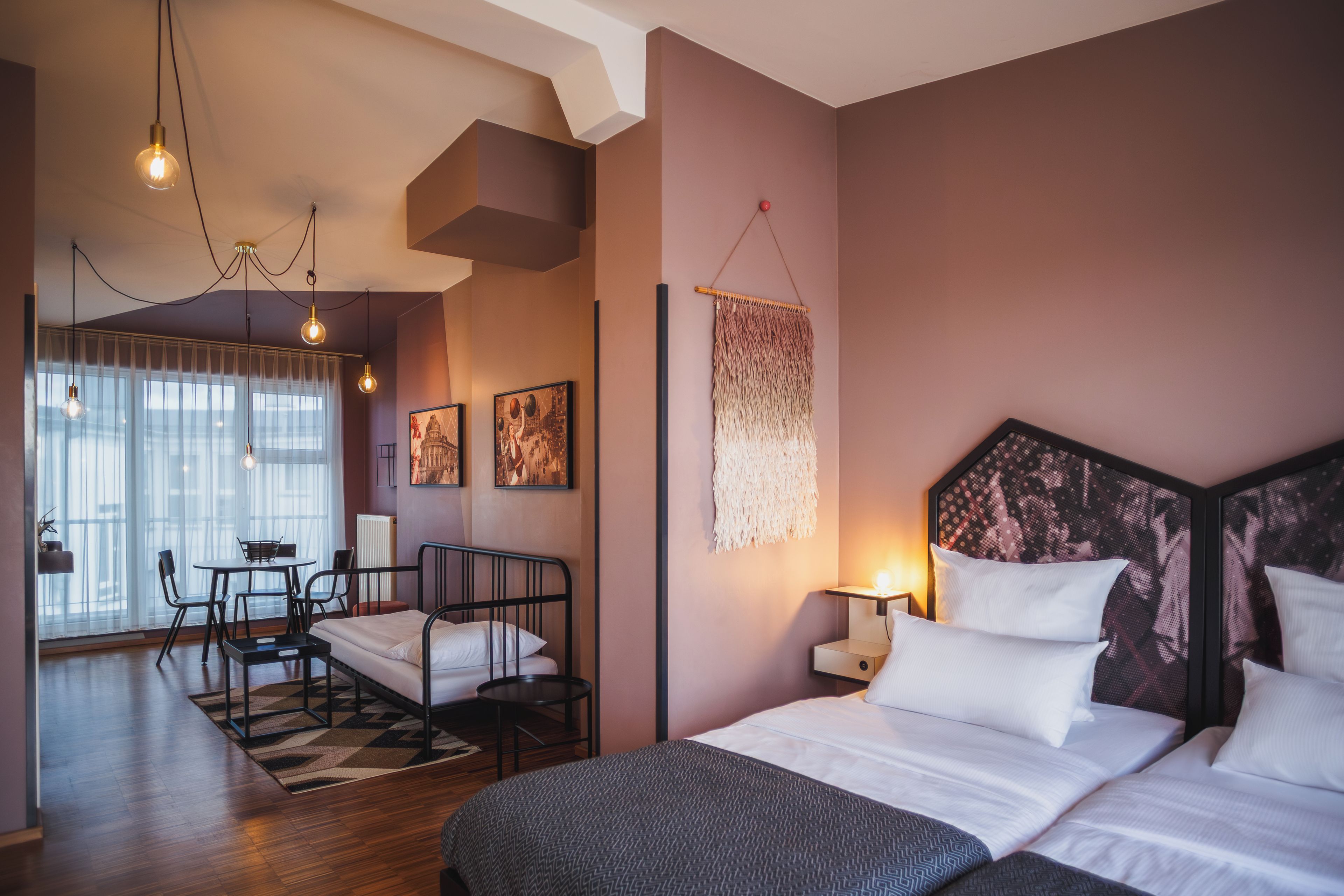 A modern hotel room with a bed, bedside table, and a view of the city.