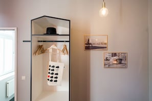 A room with a black shelving unit, a hanging light fixture, and two framed pictures on the wall. - The Circus Hostel (Berlin)