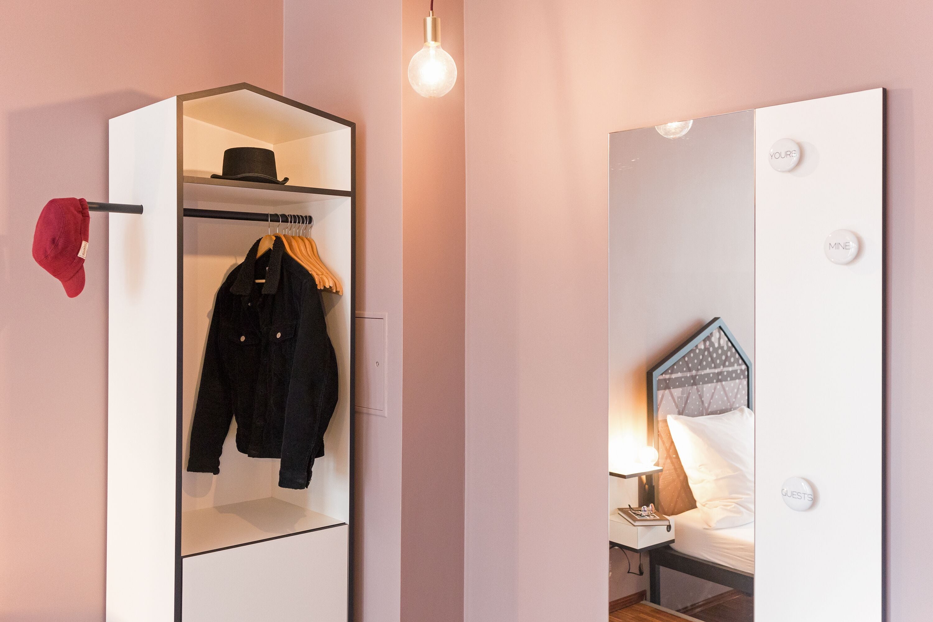 A hotel room with a wardrobe, a bed with a headboard, and a nightstand.