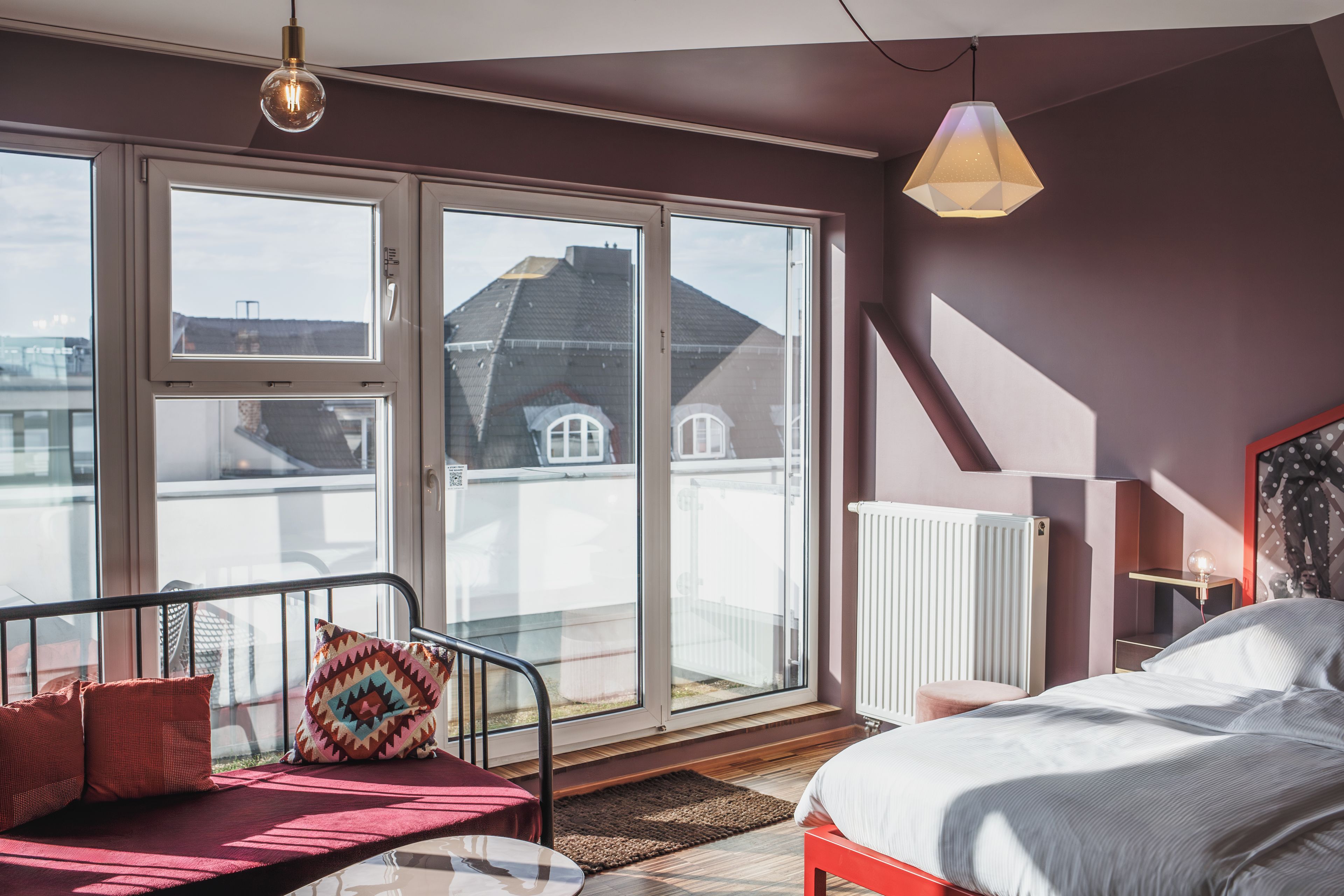 Un dormitorio con cama, sofá, ventana y radiador.