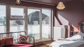 Un dormitorio con cama, sofá, ventana y radiador.