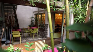 An outdoor patio area with yellow chairs and tables, surrounded by bamboo plants and potted plants. - Hotel La Chartreuse (Toulouse)