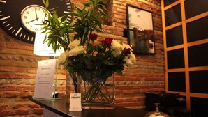 A reception desk with a clock, a vase of flowers, and a framed picture on the wall. - Hotel La Chartreuse (Toulouse)