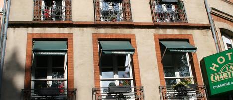 Un hotel con un letrero verde, varias ventanas y balcones.