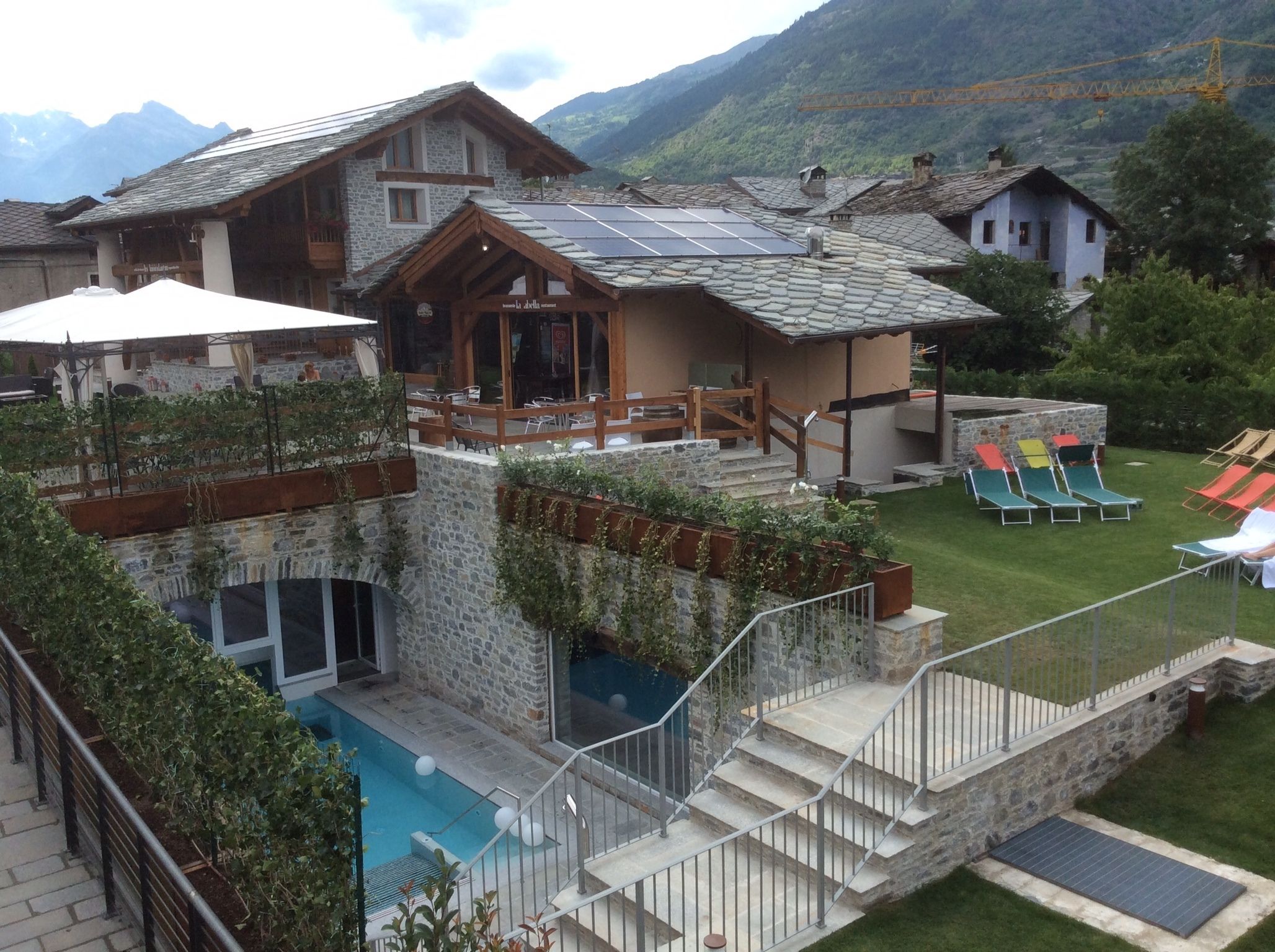 A mountain lodge with a stone exterior, a swimming pool, and a deck with lounge chairs.