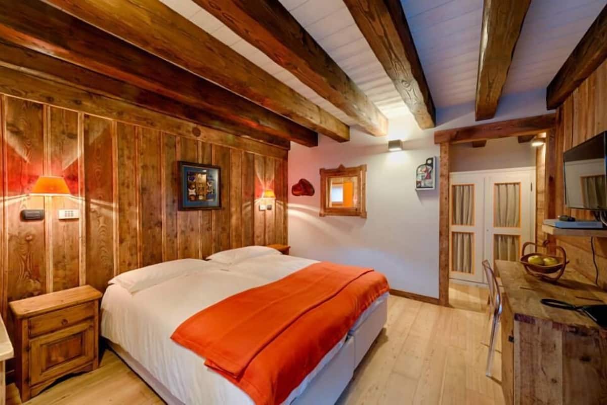 Un dormitorio con paneles de madera, una cama, mesitas de noche y un escritorio pequeño con una silla.