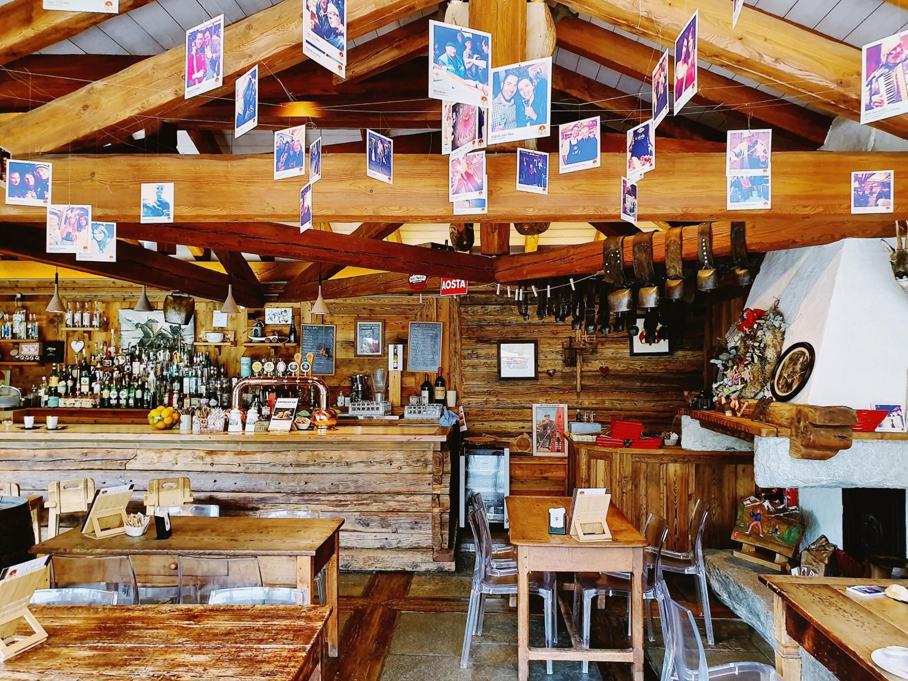 A rustic bar with wooden beams, a variety of liquor bottles, and a wooden counter.