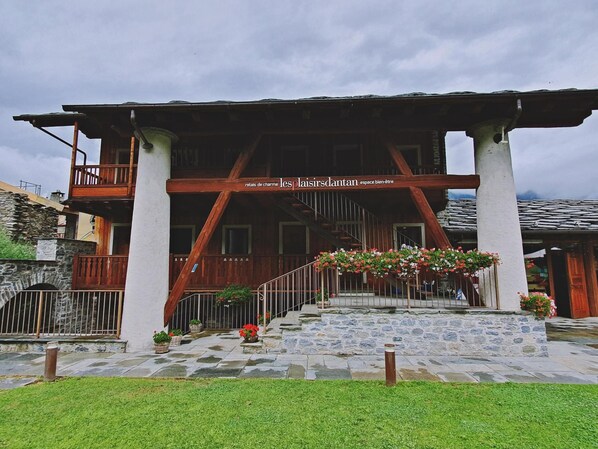 Una cabaña tradicional con fachada de madera, base de piedra y un balcón con barandillas.