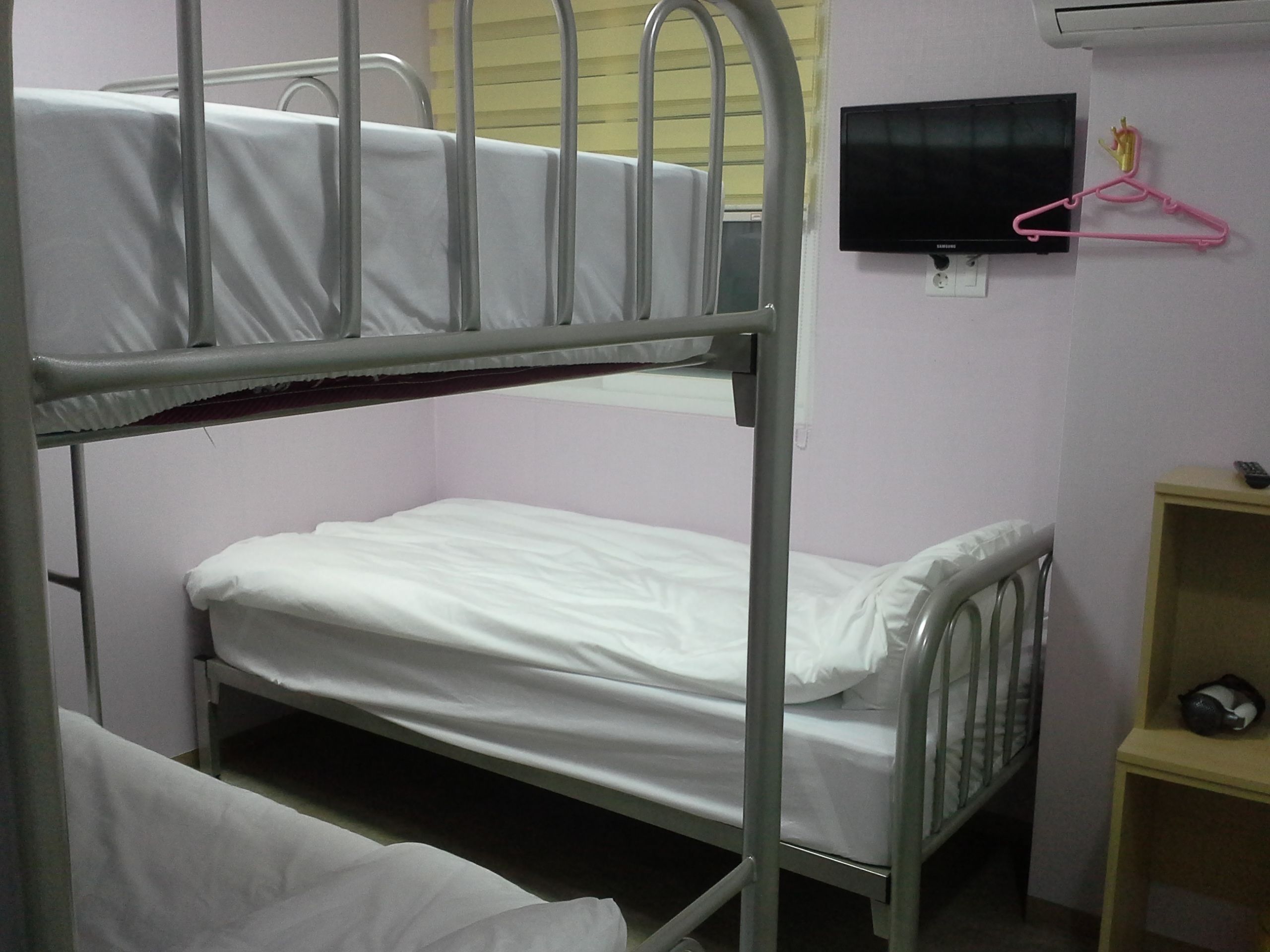 Habitación con literas, televisión y estante.