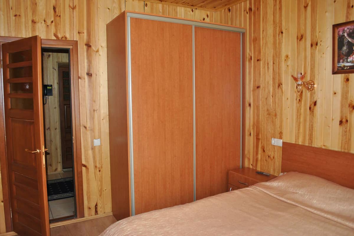 A wooden-paneled room with a wardrobe, a bed, and a small bedside table.