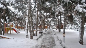 A snow-covered pathway in a park with playground equipment and benches. - Elki-Palki (Sovinion)