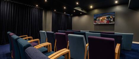 A theater with rows of seats, a dark curtain, and a wall-mounted painting.
