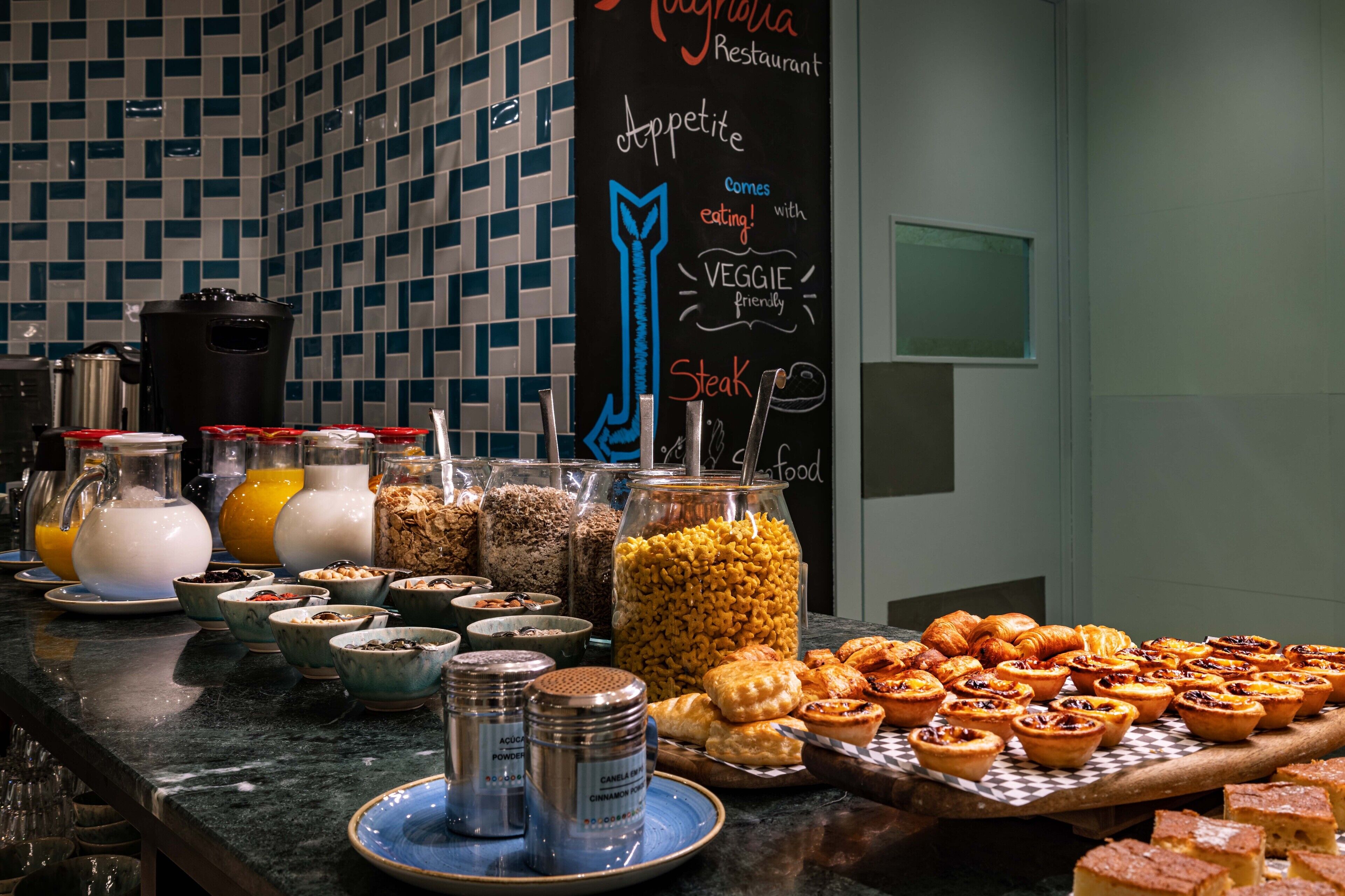 A buffet with various food items and a chalkboard sign indicating the restaurant name and menu highlights.