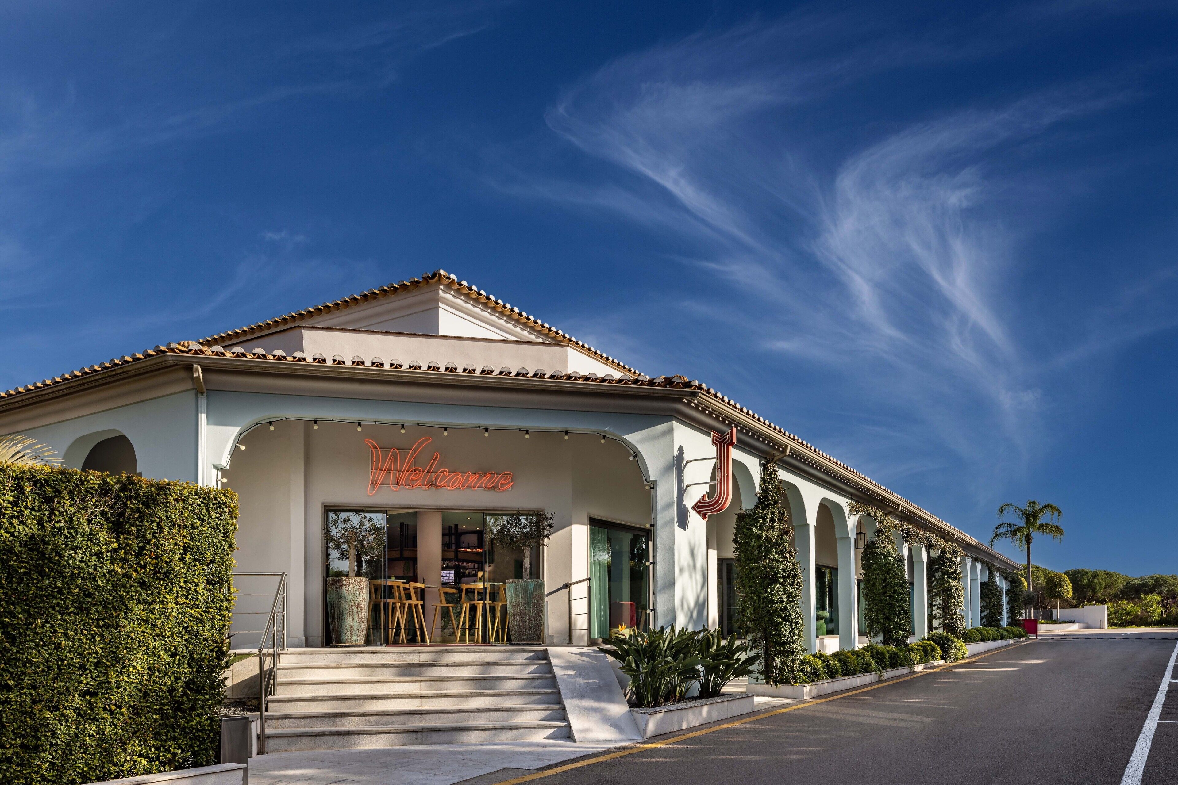 A building with a 'Welcome' sign, steps leading to the entrance, and a clear blue sky.
