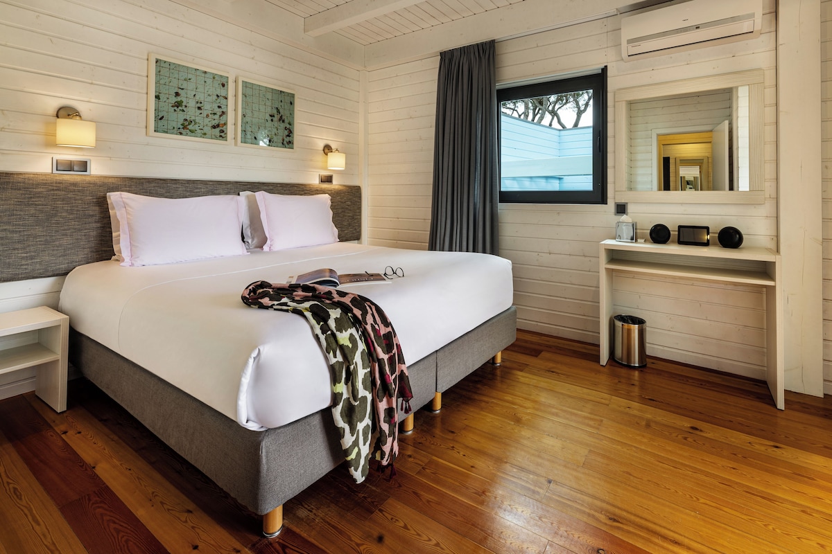 A bedroom with a bed, bedside tables, a mirror, and a window.