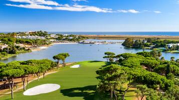 Campo de golf con un cuerpo de agua y árboles.