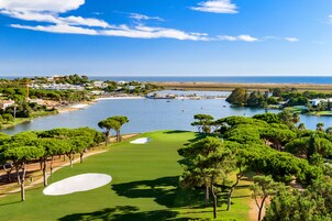 Campo de golf con un cuerpo de agua y árboles.