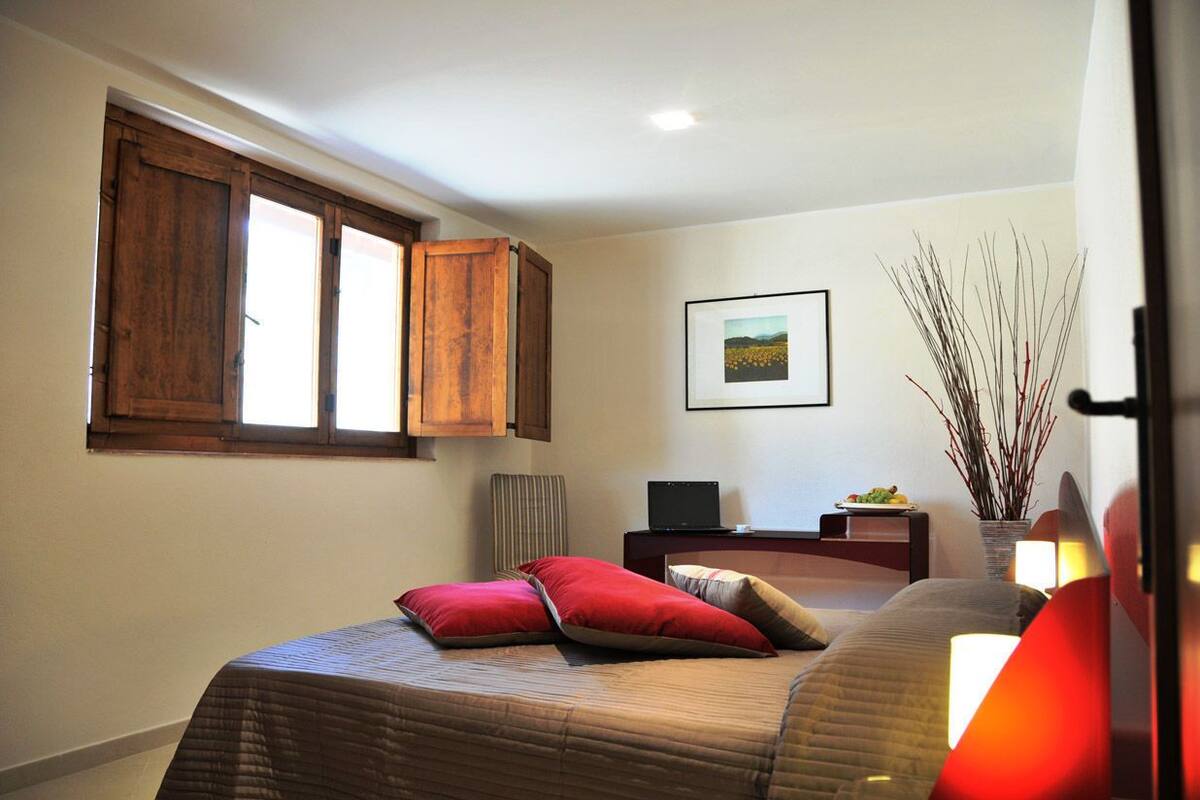 A bedroom with a bed, a desk, a chair, a window, and a picture on the wall.