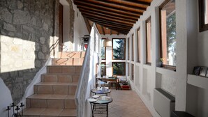 A sunlit corridor with stone walls, wooden beams, and tiled flooring. - Agriturismo Podere Assolatina (San Casciano dei Bagni)