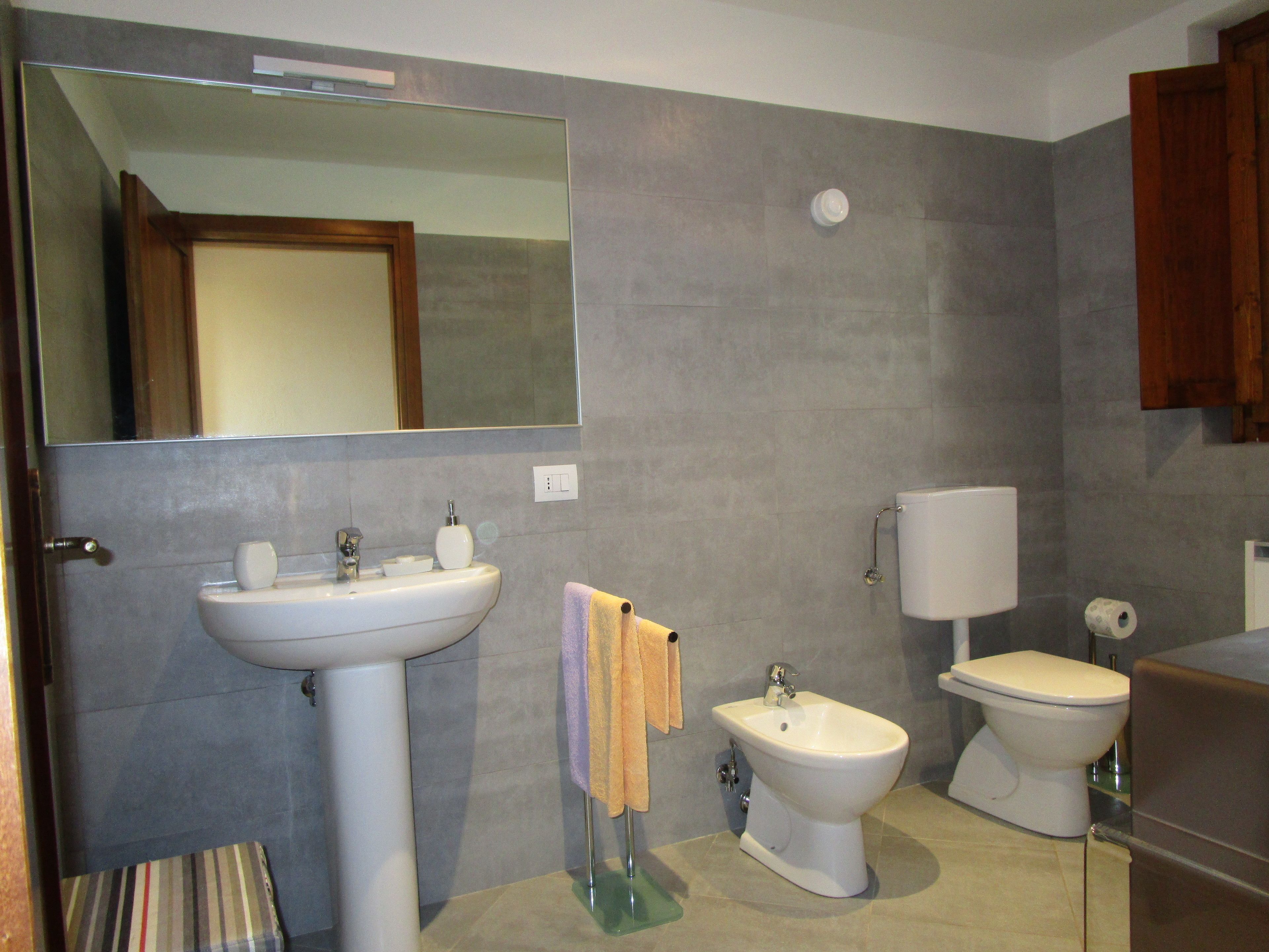 Un baño con lavamanos, bidé, inodoro y espejo.