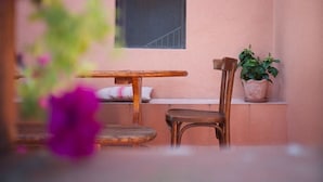 A small outdoor seating area with a wooden table and chair, a potted plant, and a window with a view of a staircase. - Agriturismo Podere Assolatina (San Casciano dei Bagni)