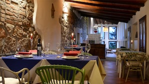 A dining area with rustic stone walls, wooden beams, and a view of the outdoors through a window. - Agriturismo Podere Assolatina (San Casciano dei Bagni)