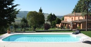 A swimming pool with a view of a house and hills in the background. - Agriturismo Podere Assolatina (San Casciano dei Bagni)
