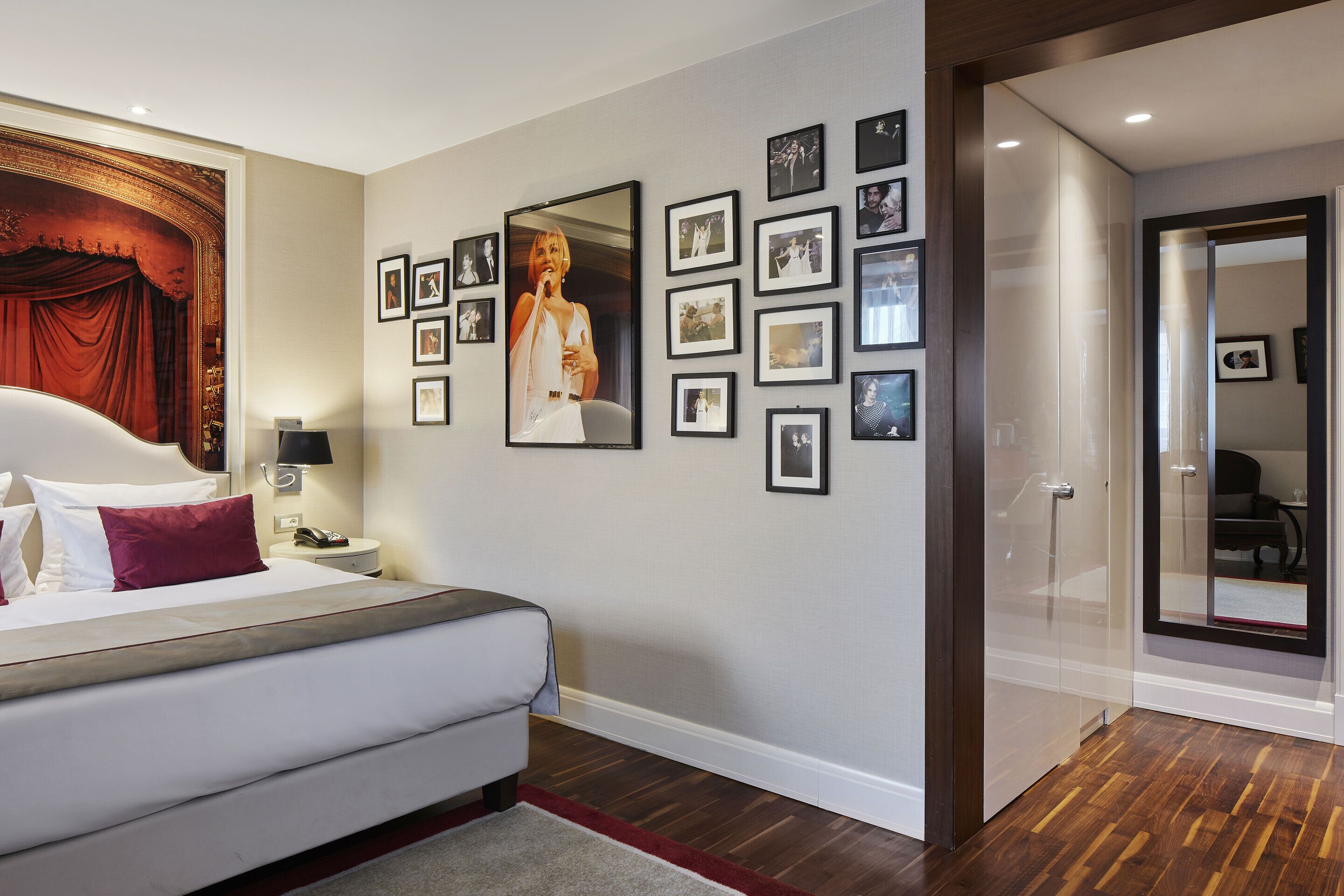 Una camera d'albergo con un letto, un quadro grande incorniciato e una parete decorata con fotografie più piccole.