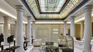 A grand lobby with high ceilings, a stained glass skylight, and classical columns. - TITANIC Gendarmenmarkt Berlin (Berlin)