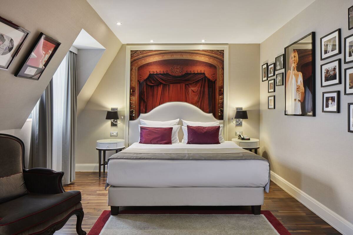 A modern bedroom with a large bed, two bedside tables, a chair, and a large mirror on the wall.