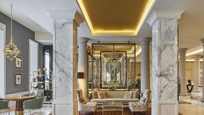 A luxurious lobby with marble columns, a grand chandelier, a central art piece, and a seating area with a coffee table. - TITANIC Gendarmenmarkt Berlin (Berlin)