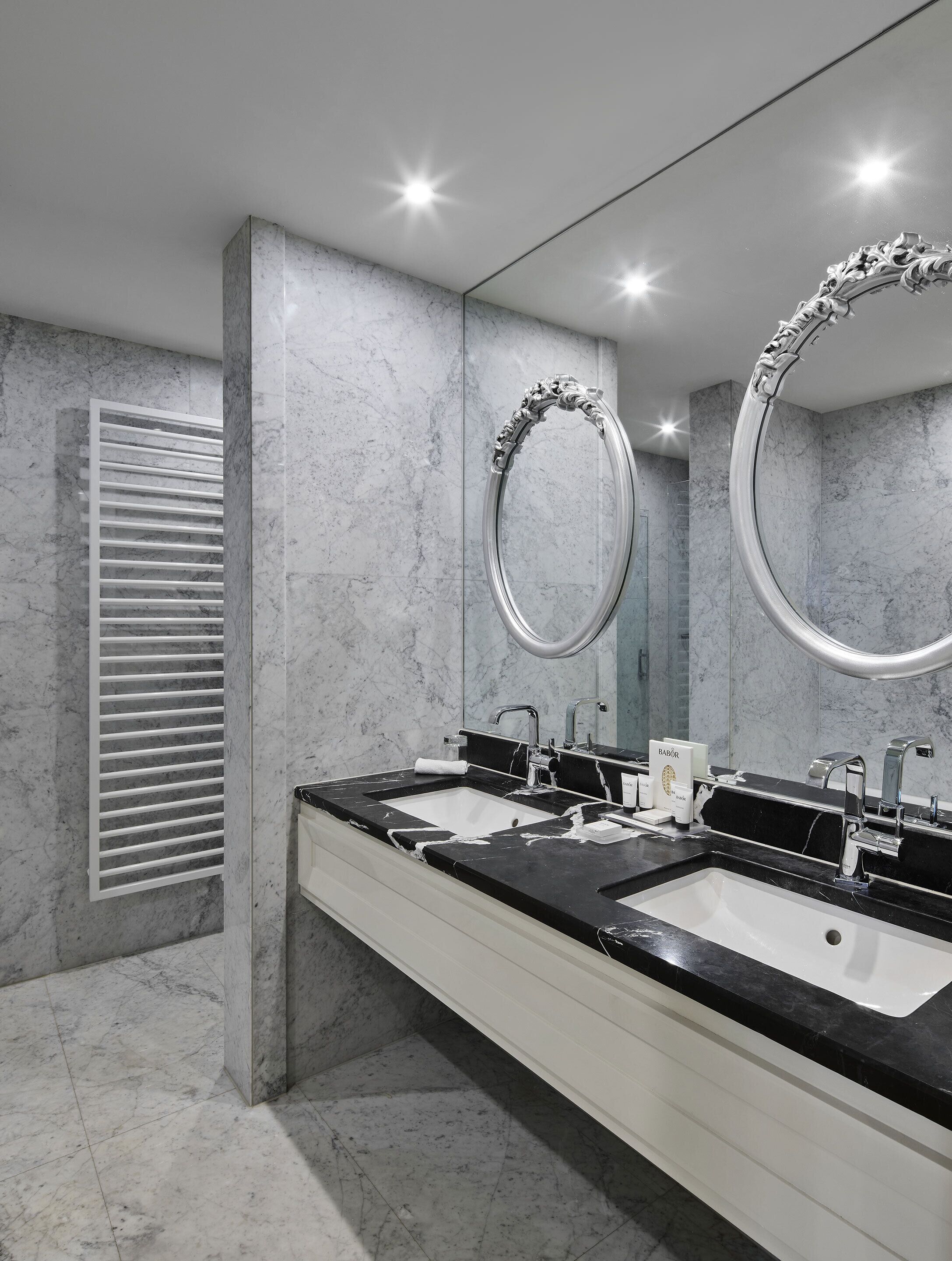 A modern bathroom with two sinks, a large mirror, and a ventilation unit.