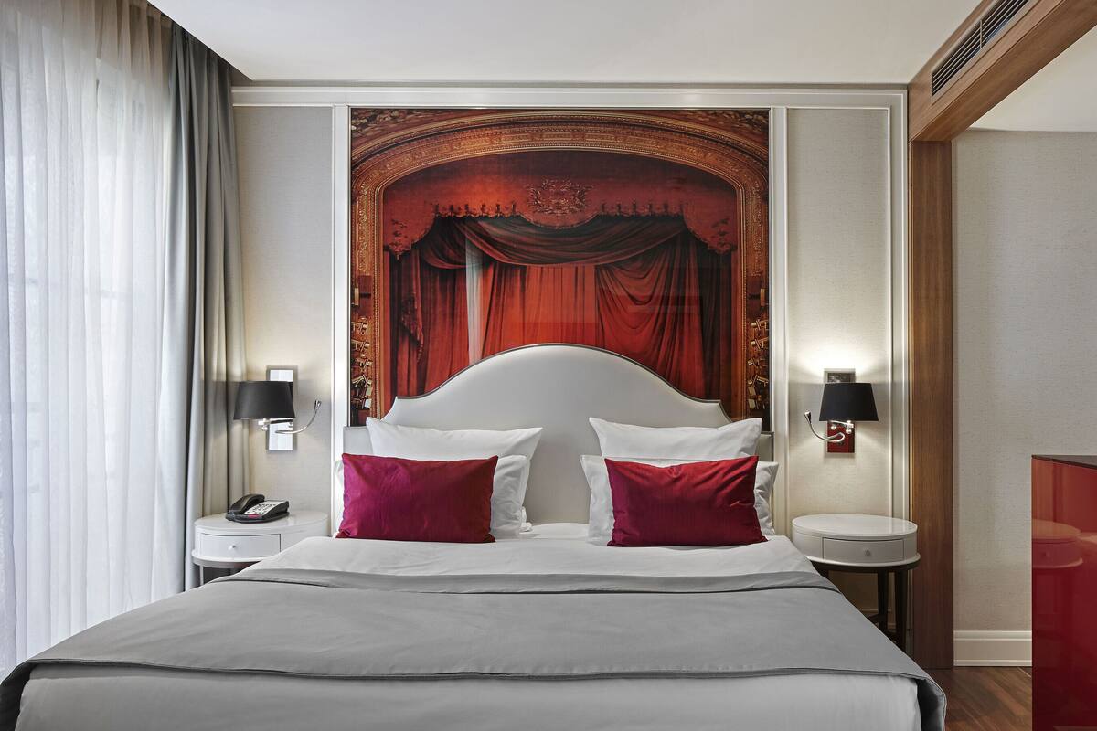 A hotel room with a large bed, two bedside tables, a telephone, and a decorative wall panel.