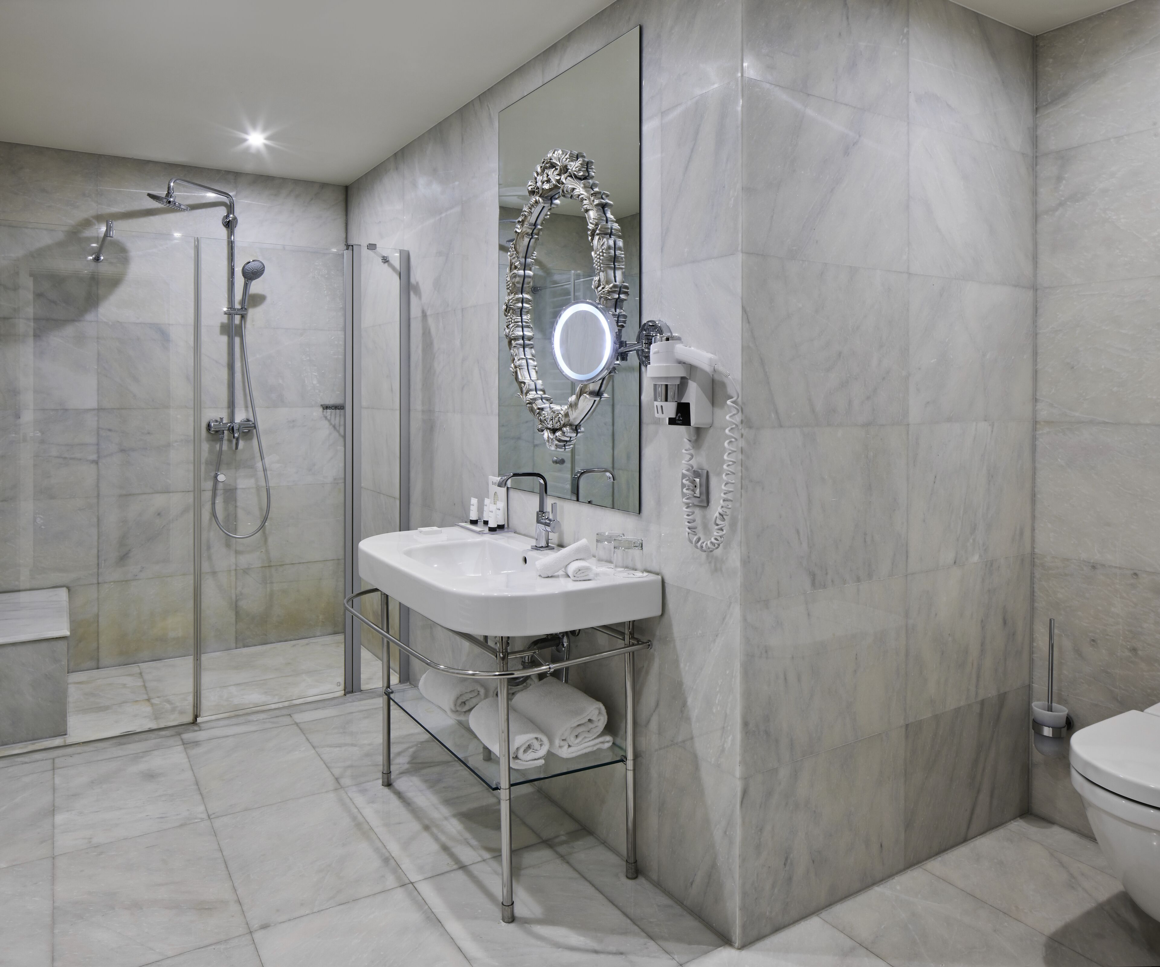 Un baño moderno con ducha de vidrio, tocador con espejo y retrete.