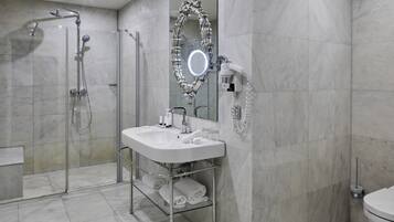 Un baño moderno con ducha de vidrio, tocador con espejo y retrete.