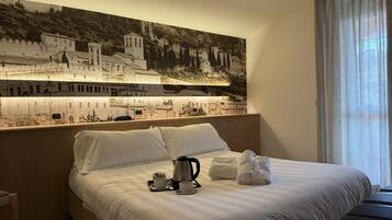 A hotel room with a large bed, a coffee maker, and a tray with cups and towels.