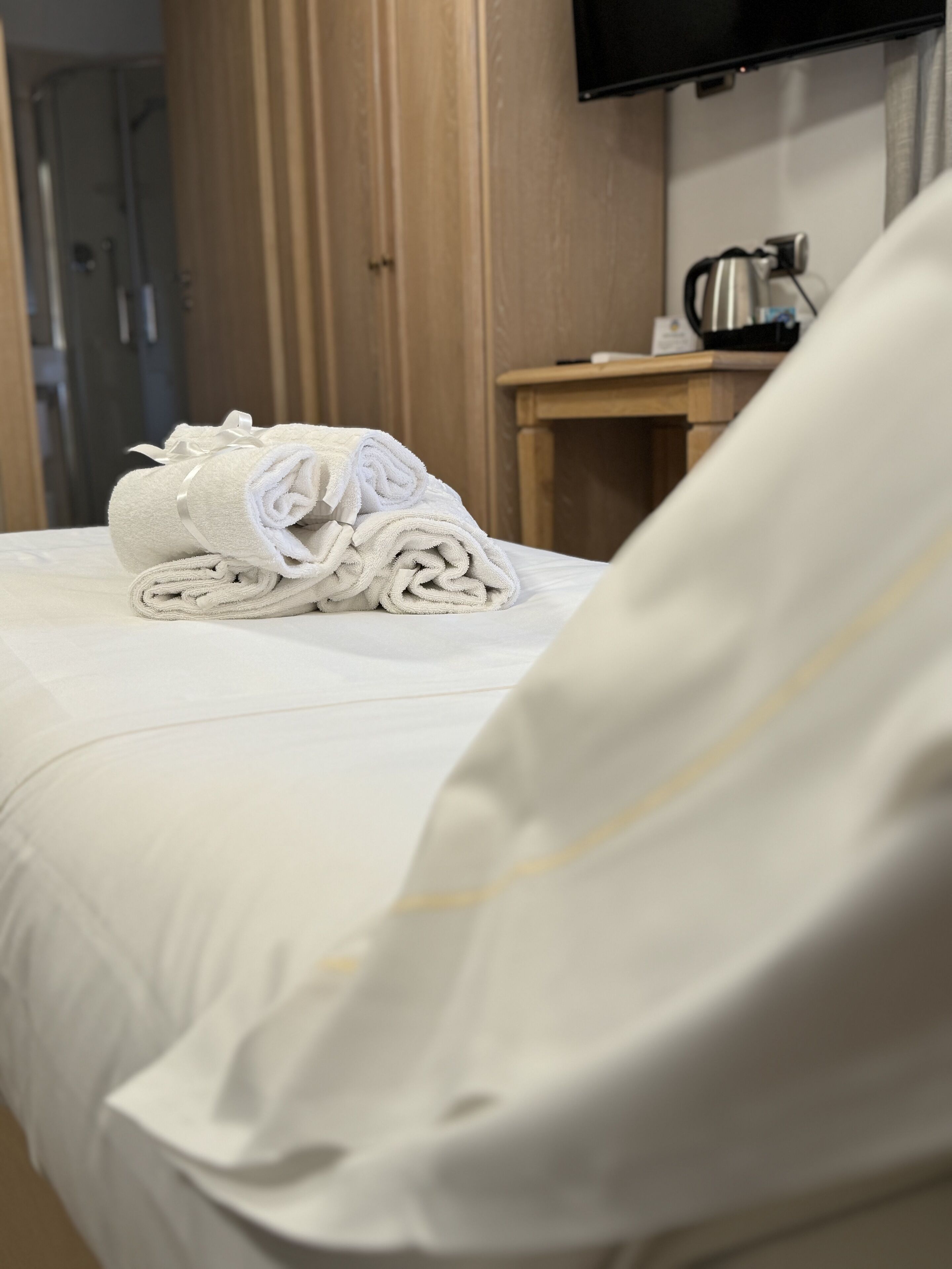 A neatly made bed with a folded towel and a pillow.