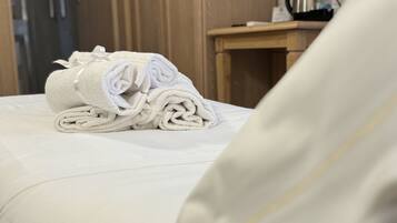 A neatly made bed with a folded towel and a pillow.