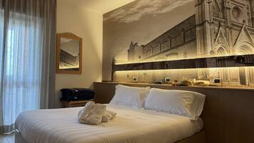 Una habitación de hotel con una cama grande, una mesita de noche, un cuadro de una catedral y una ventana con cortinas.