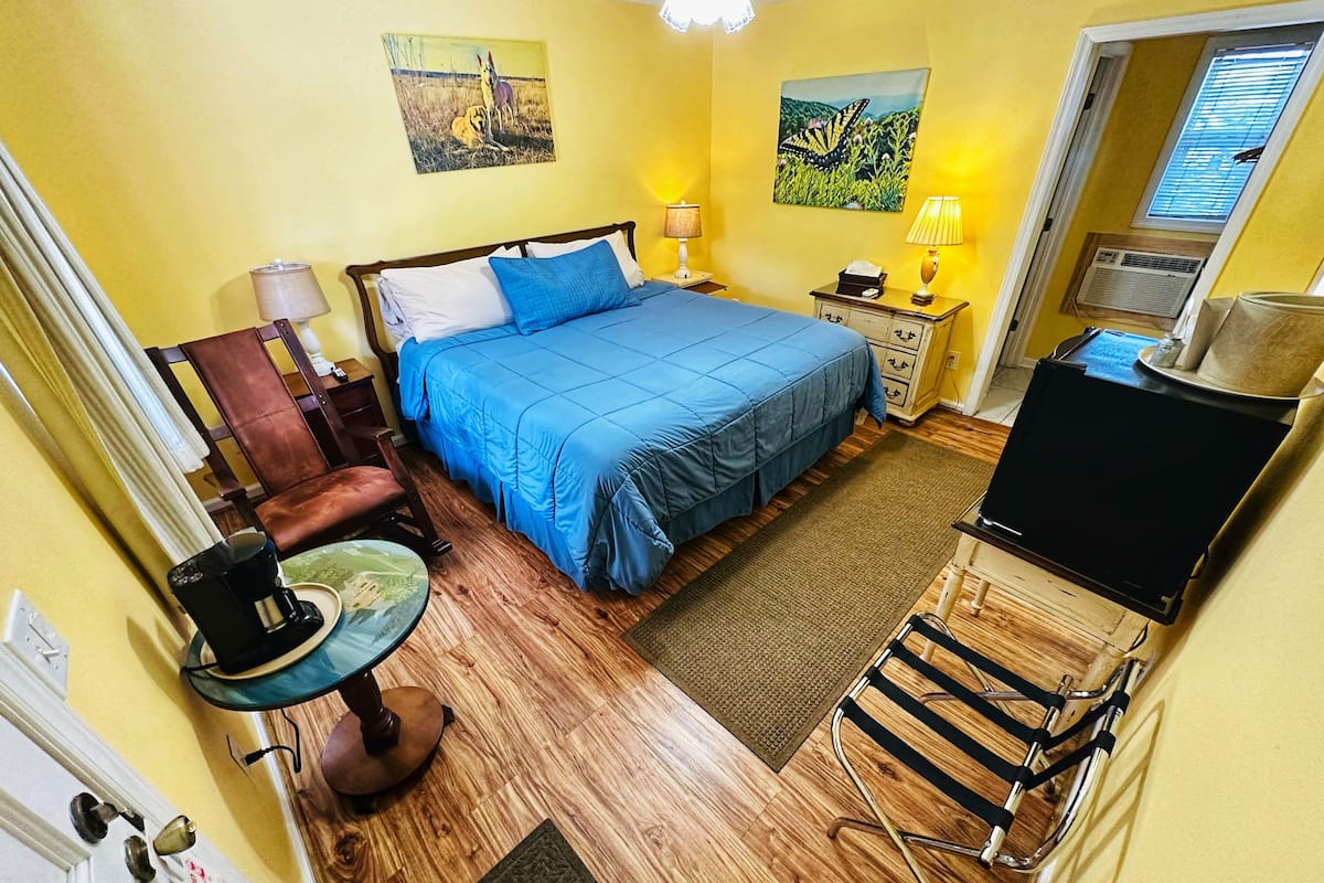 Habitación de hotel con cama, escritorio, silla, televisión y obras de arte en las paredes.