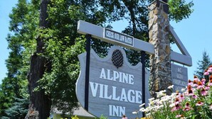 A sign for Alpine Village Inn with a stone pillar and a signboard. - Alpine Village Inn (Blowing Rock)